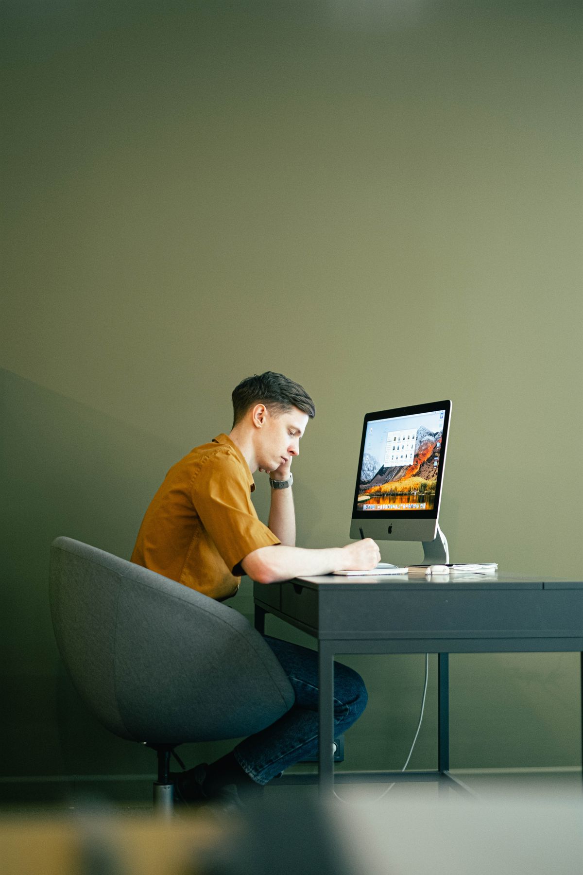 Pessoa sentada em cadeira de escritório ajustando a altura do assento em frente ao computador