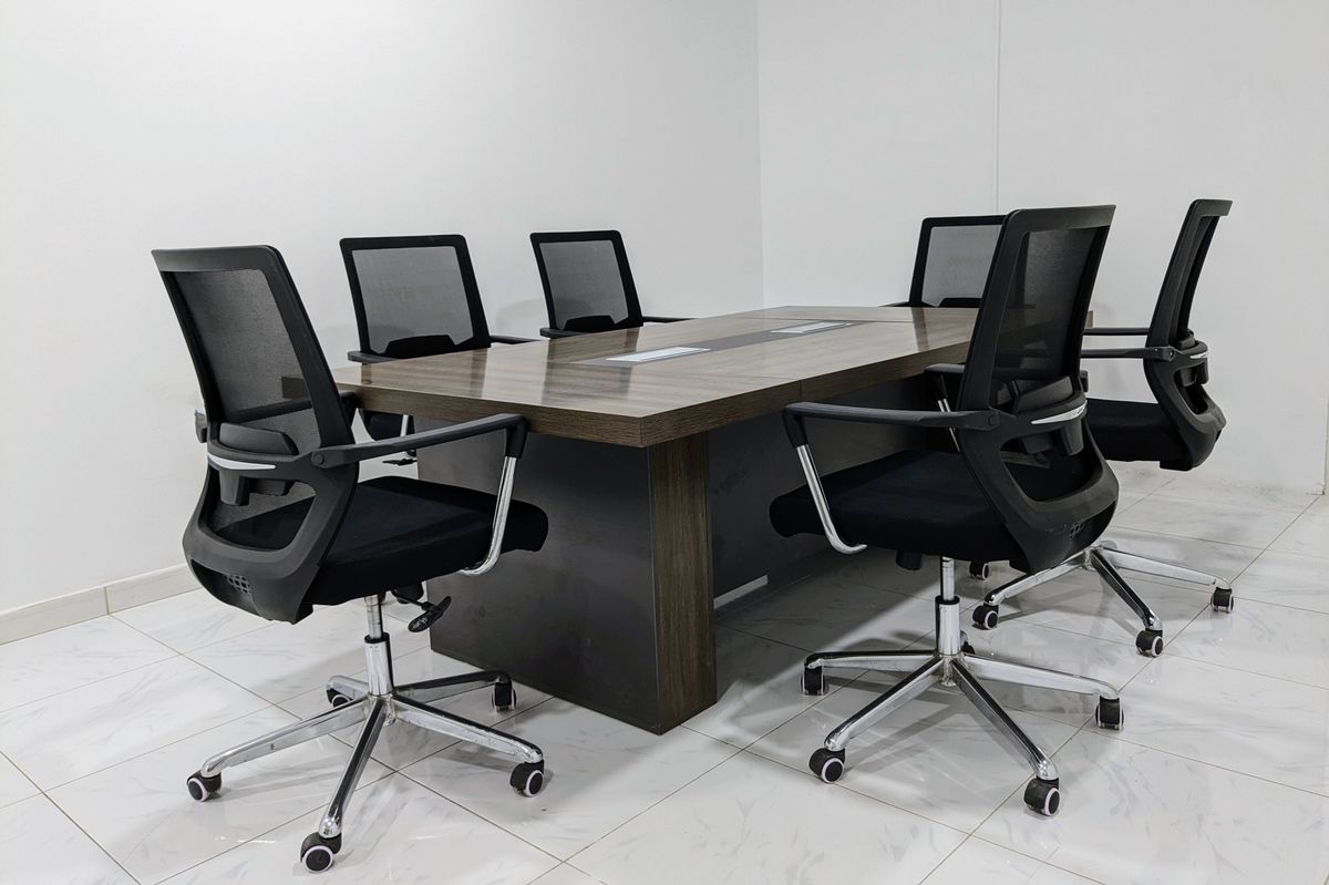 Sala de reunião moderna com mesa de conferência em madeira e cadeiras executivas pretas